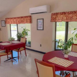 A cozy dining area with red tablecloths, plants by the windows, and warm lighting.