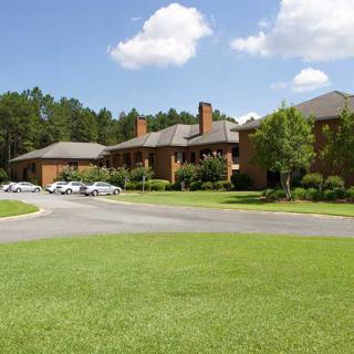 A large residential building surrounded by greenery and a clear blue sky.