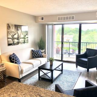 A modern living room with a comfortable sofa and armchairs, featuring a large window with a view.
