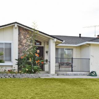 A suburban house with a well-maintained front lawn and stone facade.
