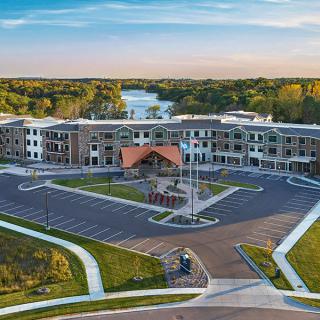 Aerial view of a large building complex surrounded by a parking lot and scenic landscape.