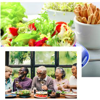 A group of people enjoying a meal together with salad and breadsticks.
