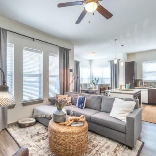 A modern, open-concept living room with a cozy sofa and stylish decor, seamlessly connected to the kitchen area.