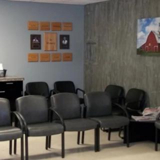 A waiting room with rows of black chairs and wall decor.