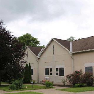 A view of a modern residential building surrounded by trees and a cloudy sky.