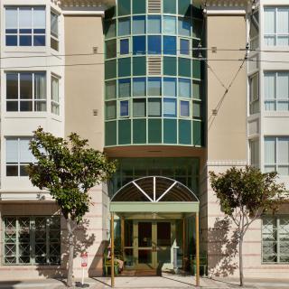 Front view of a modern apartment building with trees lining the entrance.