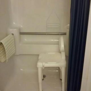 An accessible shower with a chair and handrail.