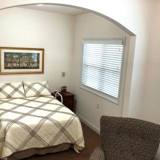 A cozy bedroom with a bed, side table, and a window with blinds.