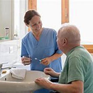 A caregiver assisting an elderly man in the bathroom.