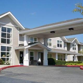 A modern residential building with a covered entrance and landscaped surroundings.