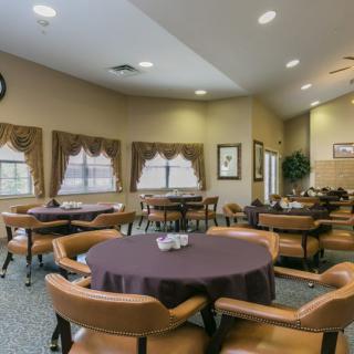 A cozy dining area with tables and chairs, featuring warm lighting.