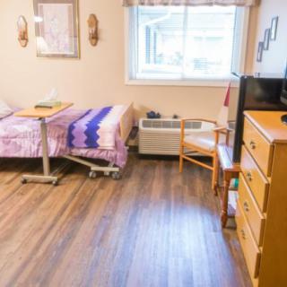 A cozy room with two hospital beds, a dresser, a chair, and a television near the window.