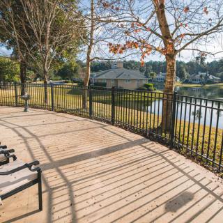 A serene park with benches overlooking a tranquil lake, surrounded by trees and illuminated by sunlight.