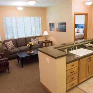 A cozy apartment interior featuring a living room with a sofa and coffee table adjacent to an open kitchen area.