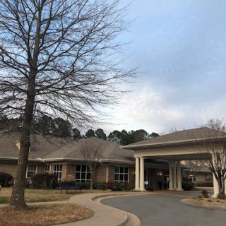 A care facility surrounded by trees under a cloudy sky.