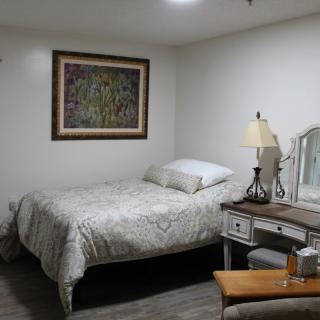 A cozy bedroom with a bed, mirror, and lamp.