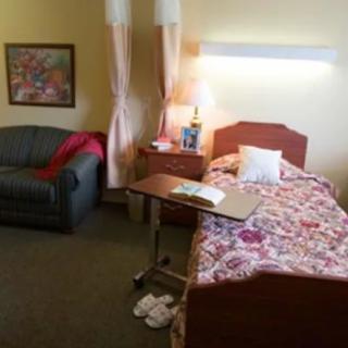 A cozy hospital room with a bed, sofa, and bedside table.