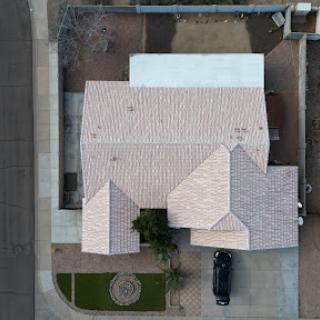 An aerial view of a residential house showcasing its roof structure and surrounding area.