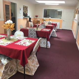 A cozy dining area set up with neatly arranged tables adorned with red tablecloths and decorative flowers.