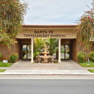 Entrance of Santa Fe Convalescent Hospital with surrounding plants and fountain.