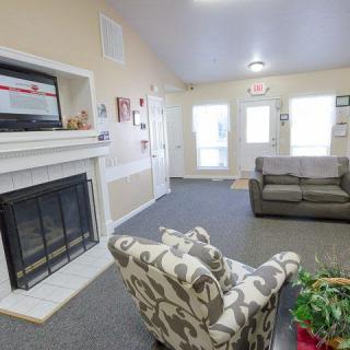 A cozy living room with a fireplace, sofa, and patterned armchair.