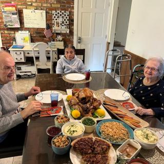 A family enjoys a meal together around the dining table, with a variety of dishes prepared for a celebration.