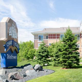 Welcome sign in front of a building surrounded by greenery and trees.