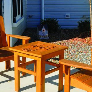 Wooden outdoor chairs and table set in a sunny patio area.