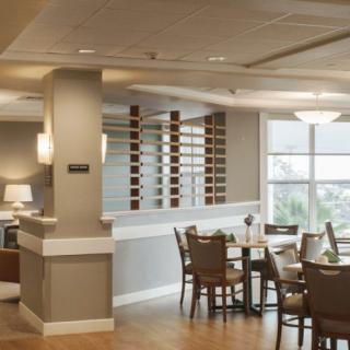 A modern dining area with neatly arranged tables and chairs, featuring large windows and stylish interior design.