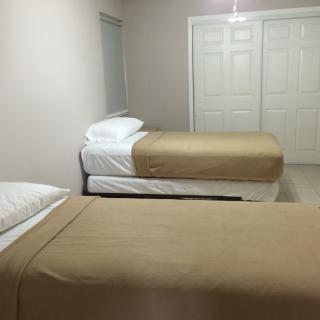 A minimalist bedroom with two neatly made single beds and a neutral color scheme.