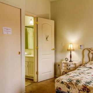 A cozy bedroom with floral bedding and a warmly lit lamp on the nightstand.