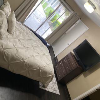 A cozy bedroom with a neatly made bed, dresser, and wall-mounted television.