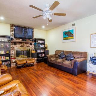 A cozy living room with a fireplace, comfortable sofas, bookshelves, and a television.