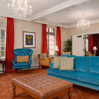 A stylish living room with a blue sofa, armchair, and chandeliers.