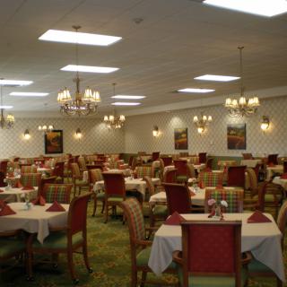 An elegantly set dining room with multiple tables and chandeliers overhead.