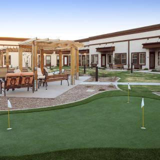 A scenic outdoor recreation area featuring a putting green and patio seating.