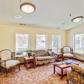 A cozy living room with sofas and chairs arranged around a central table under soft lighting.