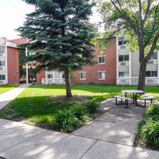 A residential apartment building with well-maintained landscaping and outdoor seating.