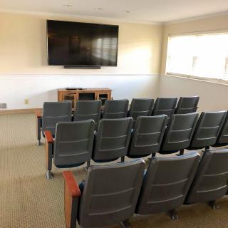 An empty conference room with tiered seating and a large television screen.