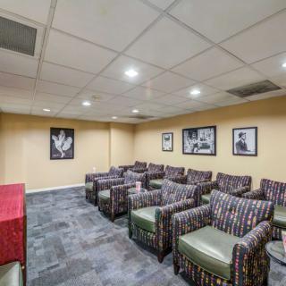 A cozy lounge area with multiple armchairs and framed pictures on the walls, suitable for meetings or relaxation.