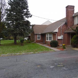 A suburban brick house with a driveway and a well-maintained yard.