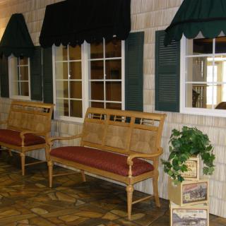 An indoor seating area with benches, windows, and green awnings.