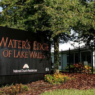 Entrance sign for Water's Edge of Lake Wales surrounded by trees and landscaping.