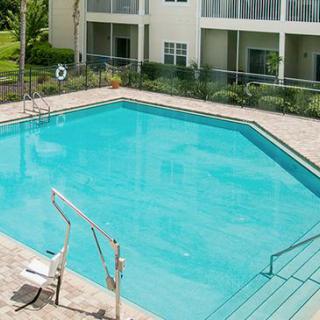 An outdoor swimming pool in a residential area with clear blue water.