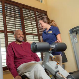 A personal trainer assists a senior client with exercise at the gym, promoting health and fitness.