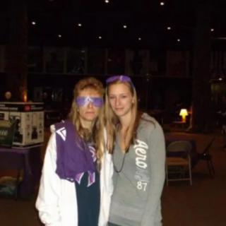 Two friends posing together indoors with casual outfits and purple accessories.