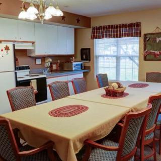 A cozy dining room with a large table and chairs, adjacent to a kitchen area.