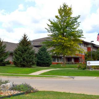 A building surrounded by greenery with a flag and a driveway.
