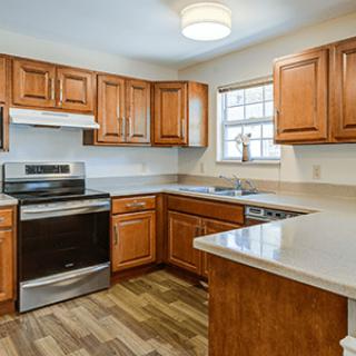 A modern kitchen with wooden cabinets, featuring an oven and stove, sink, and ample countertop space.