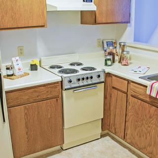 A small kitchen with wooden cabinets and an electric stove.